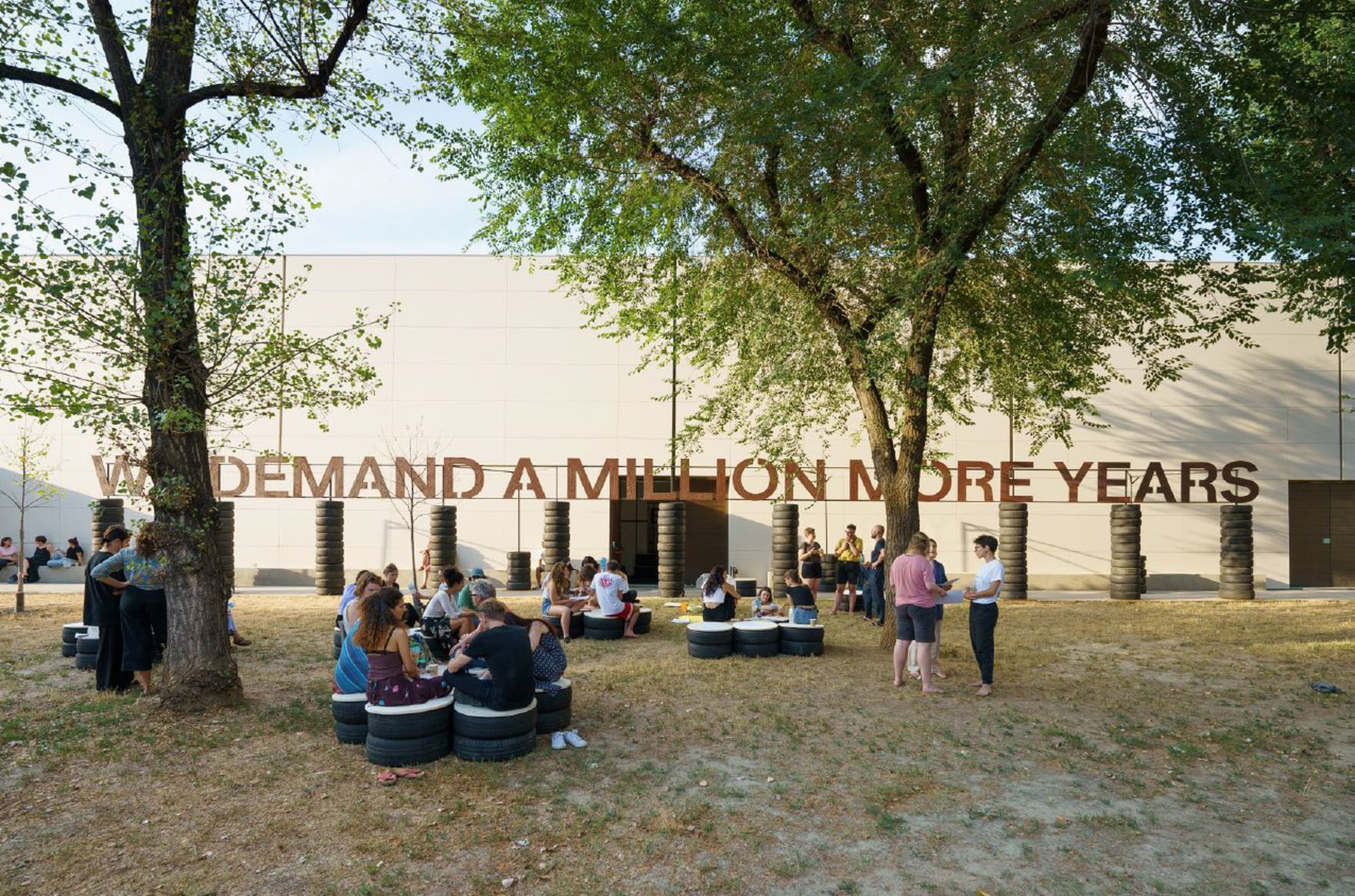 We Demand a Million More Years (text piece # 2022 Jonas Staal Wood, paint, soil, steel, defunct car tires, approximately 300x2970 cm