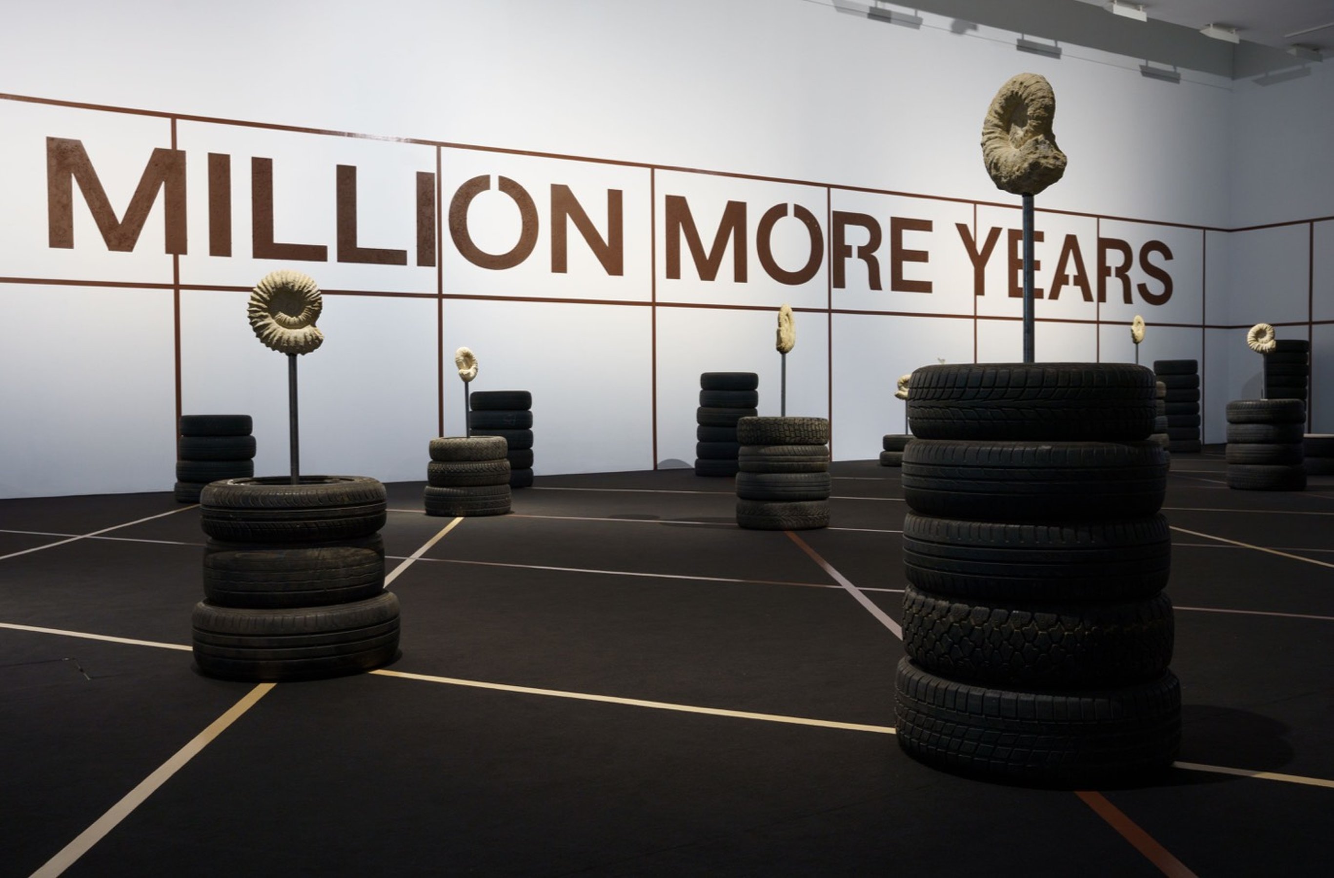 Jonas Staal WE DEMAND A MILLION MORE YEARS (medium sculpture), 2022 ​​​​​​​Ammonite fossils of approximately 100 million years old, metal rods, hardened oil, 3 defunct car tires